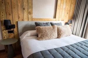 una camera da letto con letto, lenzuola e cuscini bianchi di Borda Conangle Mountain Lodge a Sant Julià de Lòria