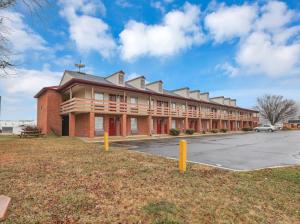 un gran edificio de ladrillo rojo con aparcamiento en Red Roof Inn Uhrichsville, en Uhrichsville