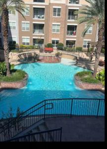 a swimming pool with blue water in front of a building at Home felt apartment- Med Center/NRG in Houston
