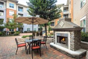 a patio with a table with an umbrella and a fireplace at Home felt apartment- Med Center/NRG in Houston
