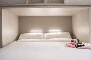 a white bed with a pair of shoes sitting on it at room007 Salvador Hostel in Seville