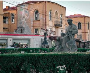 Una statua di un uomo seduto su una panchina di Aros Apartment a Gyumri