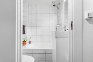 a white bathroom with a tub and a sink at Demims Apartments Oslo -- Cozy, Central & Stylish in Oslo