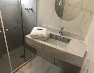 a bathroom with a shower and a sink with a mirror at Gonzaga Flat in Santos