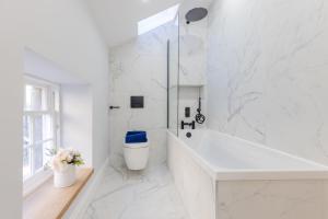baño blanco con bañera y aseo en Dragon Suites - Yukina Suite - 2 bed city centre house with garden, en Edimburgo