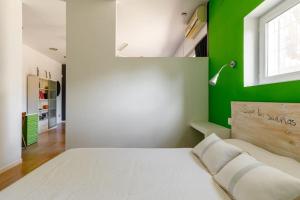 a bedroom with a white bed with a green wall at Desconectar en El Vedat. in Torrent