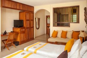 Cette chambre comprend un lit, un canapé et une télévision. dans l'établissement Vanila Hotel & Spa, à Ambaro