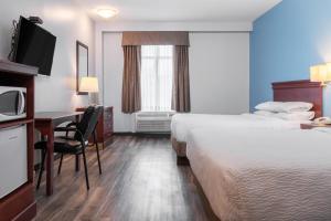 een hotelkamer met 2 bedden, een bureau en een televisie bij Premier Inn & Suites - Downtown Hamilton in Hamilton