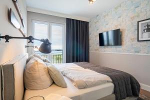 1 dormitorio con 1 cama y TV en la pared en Appartmenthaus-Suedstrand-44-Wohnung-9-Seestern, en Großenbrode