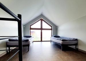 a attic room with two beds and a window at Domki Przy Tężni in Karwia
