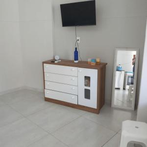 a room with a dresser with a television and a mirror at Edícula no centro de VR in Volta Redonda