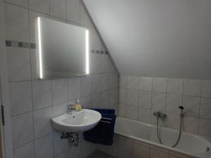 a white bathroom with a sink and a bath tub at Strandrose in Friedrichskoog +13 photos