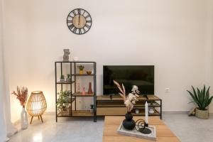 a living room with a tv and a clock on the wall at Helena's Apartment in Corfu town in Corfu