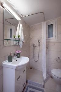 a white bathroom with a sink and a shower at Helena's Apartment in Corfu town in Corfu