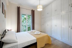 a bedroom with a bed with white cabinets and a window at Helena's Apartment in Corfu town in Corfu
