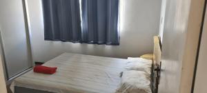 a bedroom with a bed with a red pillow on it at Apt(2) no centro de VR tudo perto até 7 pessoas in Volta Redonda