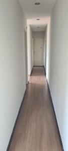 an empty hallway with white walls and a wooden floor at Apt(2) no centro de VR tudo perto até 7 pessoas in Volta Redonda