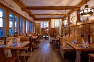 un restaurante con mesas y sillas de madera y ventanas en Hotel Pollux, en Zermatt