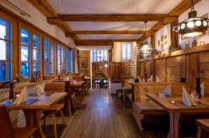 ツェルマットにあるホテル ポルクスの木製のテーブルと椅子、窓のあるレストラン