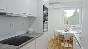 uma cozinha branca com uma pequena mesa e uma janela em Apartment No15 em Koprivnica