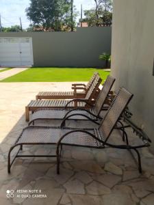 eine Gruppe von drei Stühlen auf einer Terrasse in der Unterkunft Casa acolhedora, bem aconchegante com piscina. in Brotas