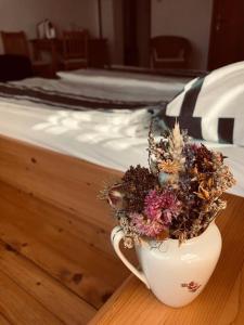 a white cup with a plant in it next to a bed at Ferienhof am Landsberg in Obergrünburg