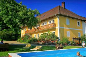 a yellow house with a swimming pool in front of it at Ferienhof am Landsberg in Obergrünburg