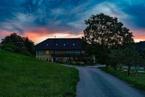 una casa en una colina con un árbol y un camino en Ferienhof am Landsberg, en Obergrünburg