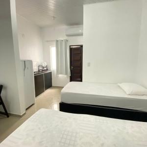 Cette chambre blanche comprend deux lits et une cuisine. dans l'établissement Hotel SALINE PRAIA, à Salinópolis