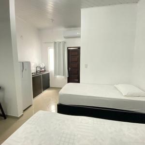 Cette chambre blanche comprend deux lits et une cuisine. dans l'établissement Hotel SALINE PRAIA, à Salinópolis