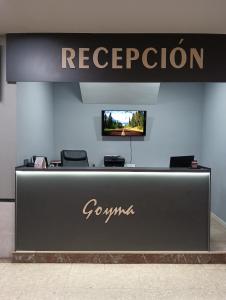 a reception desk with a television on a wall at Hostal Goyma I in San Fernando de Henares