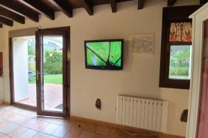 sala de estar con TV de pantalla plana en la pared en Casa de aldea el Toral, en Rales