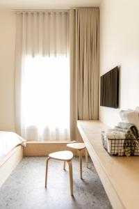 1 dormitorio con cama, mesa y TV en Petit hôtel de la Montagne en Havre-Aubert