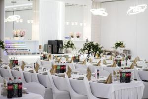 Pokój z białymi stołami, białymi krzesłami i kwiatami w obiekcie Hotel Ambrozja w mieście Sierpc