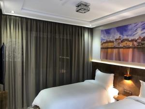 Hotel Appartement Tanger في طنجة: غرفة نوم بسريرين ولوحة على الحائط
