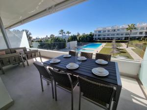 a black table and chairs on a balcony with a pool at Noctua Estepona Luxury Apartment Belair 005 in Estepona