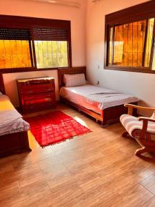 een slaapkamer met 2 bedden en een rood tapijt bij Dar Khalti - Cascades - Piscine - Montagne in Ouzoud