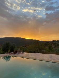 a swimming pool with the sunset in the background at Dar Khalti - Cascades - Piscine - Montagne in Ouzoud