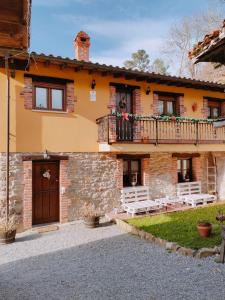 a stone house with a balcony and a patio at Carroceu Rural in Cangas de Onís