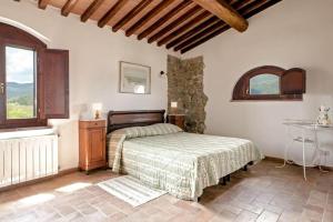 1 dormitorio con cama, mesa y ventana en Agriturismo Fattoria di Statiano en Pomarance