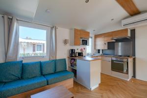 uma sala de estar com um sofá azul e uma cozinha em Mobil Home Manon em Fréjus