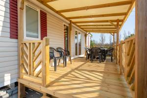 a wooden deck with chairs and tables on a house at Mobil Home Manon in Fréjus