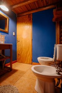 a bathroom with a toilet and a blue wall at Namasté Cabaña Tandil in Tandil