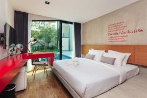 沙美岛Stellars Samed Resort的一间卧室配有一张大床和一张红色的书桌