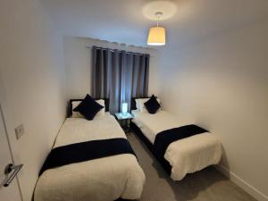 two beds in a room with a window at New build home with WI-FI, Smart TV, dedicated office floor, large terrace and Free parking in Milton Keynes