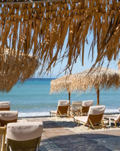a group of chairs and umbrellas on a beach at Georgalas Rest Apartments in Nea Kallikrateia