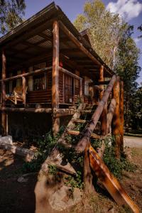 a log cabin with a wooden staircase leading to a porch at Namasté Cabaña Tandil in Tandil