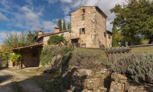 an old stone house in a field with a fence at Casavecchia 12 by Salogi Villas in Volpaia