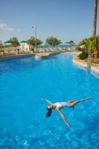 Ein Mann, der im Pool im Wasser liegt. in der Unterkunft AluaSoul Palma Hotel Adults Only in Can Pastilla