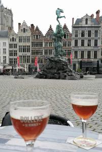 twee glazen wijn zittend op een tafel voor een standbeeld bij Historical center Antwerp, all on foot in Antwerpen